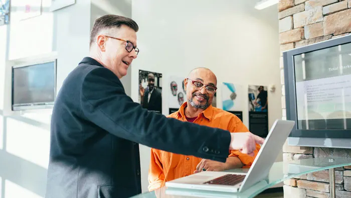 Two people smiling around an office computer