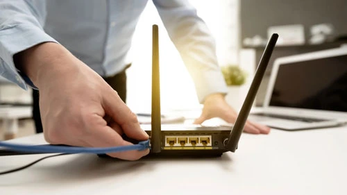 Person plugging ethernet cable into wireless router