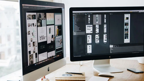 iMac computer with secondary screen showing graphics design