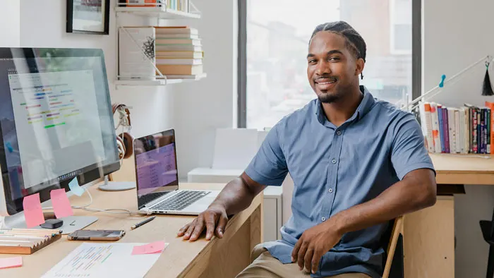 A smiling man sitting at his home computer station