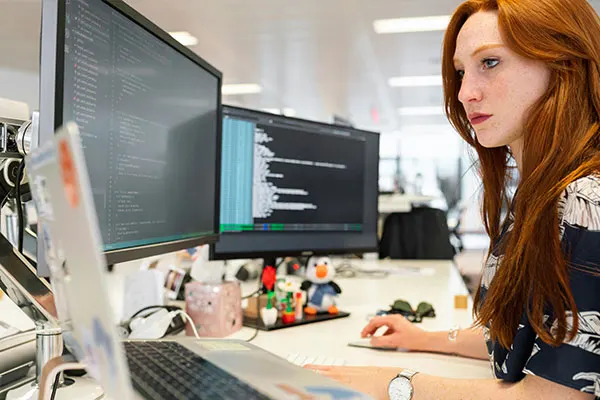 A web developer working on a computer with multiple screens